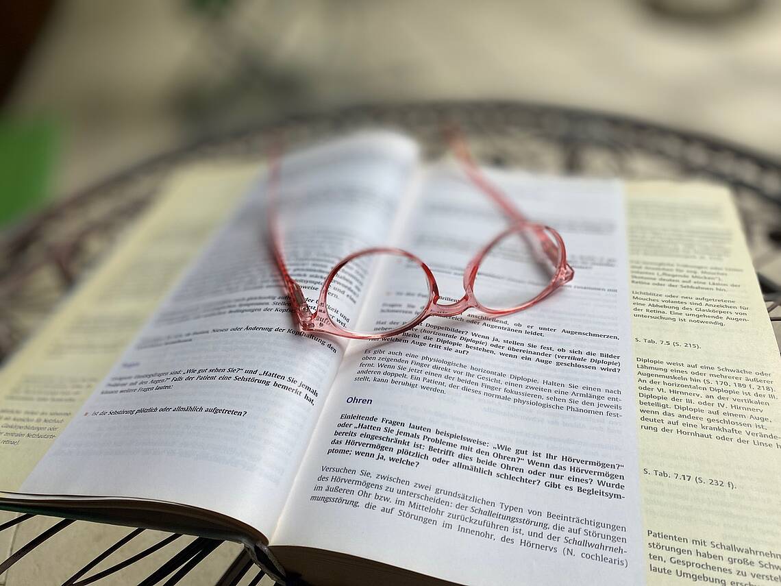 Bild von einer Brille, die auf einem Buch abgelegt ist. Foto: Heilpraktikerschule Luzern